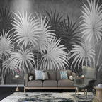 Papier peint panoramique Palmes noir et blanc : grandes palmes en éventail blanches et gris anthracite sur fond gris patiné, posé derrière un canapé