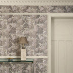 Papier peint panoramique Verdure ancienne taupe : verdure ancienne taupe sur un mur à cimaise, lampe en pierre et porte moulurée crème