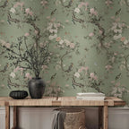 Papier peint panoramique Chinoiserie branches de pivoines vert amande : chinoiserie aux branches de pivoines et oiseaux sur fond vert amande, derrière une console en bois et un vase noir