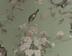 Papier peint panoramique Chinoiserie branches de pivoines vert amande : détail du motif, oiseau posé parmi les pivoines
