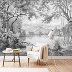 Papier peint panoramique Lac tropical gravé noir et blanc : lac bordé de grands arbres et de fougères, gravé en noir et blanc, posé derrière un fauteuil