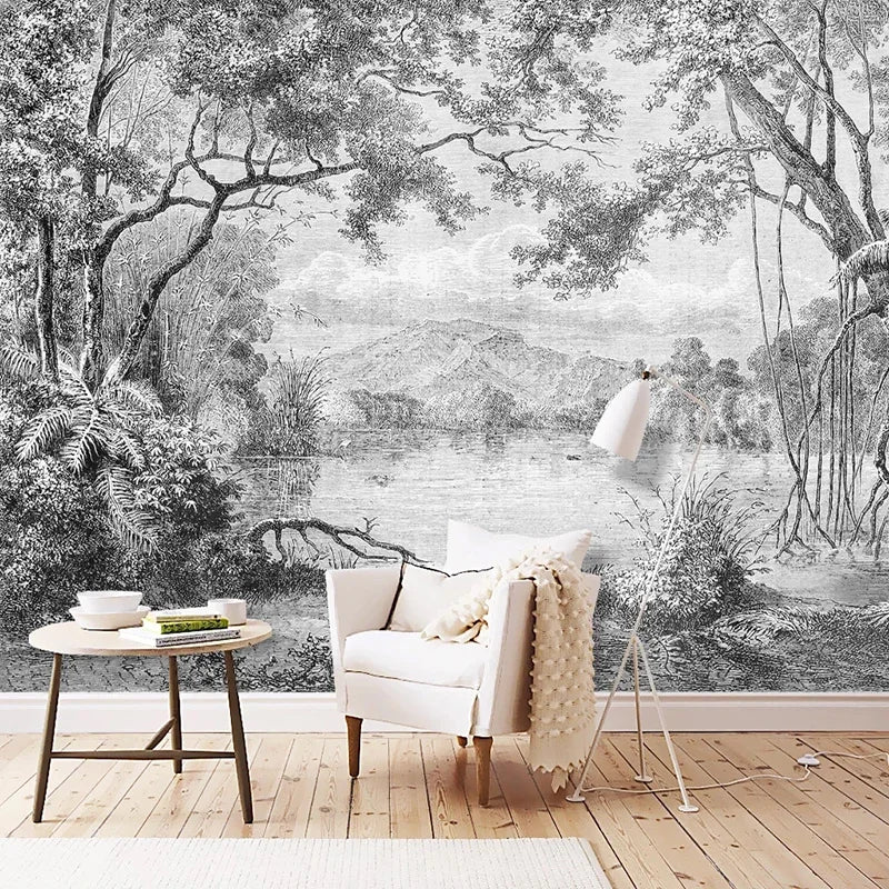 Papier peint panoramique Lac tropical gravé noir et blanc : lac bordé de grands arbres et de fougères, gravé en noir et blanc, posé derrière un fauteuil