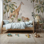 Papier peint panoramique Safari aquarelle : girafe, zèbre et palmiers à l'aquarelle, posé derrière un lit d'enfant