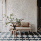 Papier peint effet pierre calcaire gris clair : effet pierre calcaire claire et mouchetée derrière une banquette ancienne, sol en damier