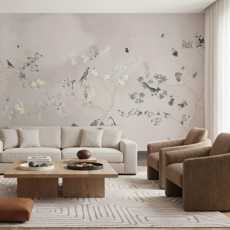 Papier peint panoramique Chinoiserie oiseaux et arbres fleuris rose poudré : chinoiserie rose poudré aux arbres fleuris et aux oiseaux derrière un canapé lin et deux fauteuils bruns