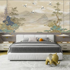 Papier peint panoramique Chinoiserie grues et montagnes sable : grues blanches au-dessus de montagnes brumeuses et d'arbres peints sur fond sable, derrière une tête de lit