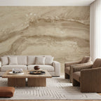 Papier peint effet travertin sable : effet travertin sable veiné de beige et de brun doux, derrière un canapé clair et des fauteuils en velours