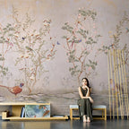 Papier peint panoramique Chinoiserie faisans et étang mauve poudré : chinoiserie aux faisans et arbustes fleuris sur fond mauve poudré patiné, banquette basse et bambous