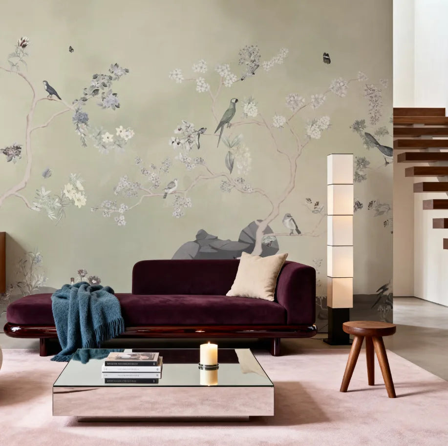 Papier peint panoramique Chinoiserie oiseaux et arbres fleuris vert sauge : chinoiserie vert sauge aux arbres fleuris et aux oiseaux derrière un canapé prune, lampe en papier