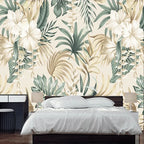 Papier peint panoramique Hibiscus et feuillages sauge : fleurs d'hibiscus blanches, feuillages vert sauge et palmes sable sur fond crème, derrière un lit