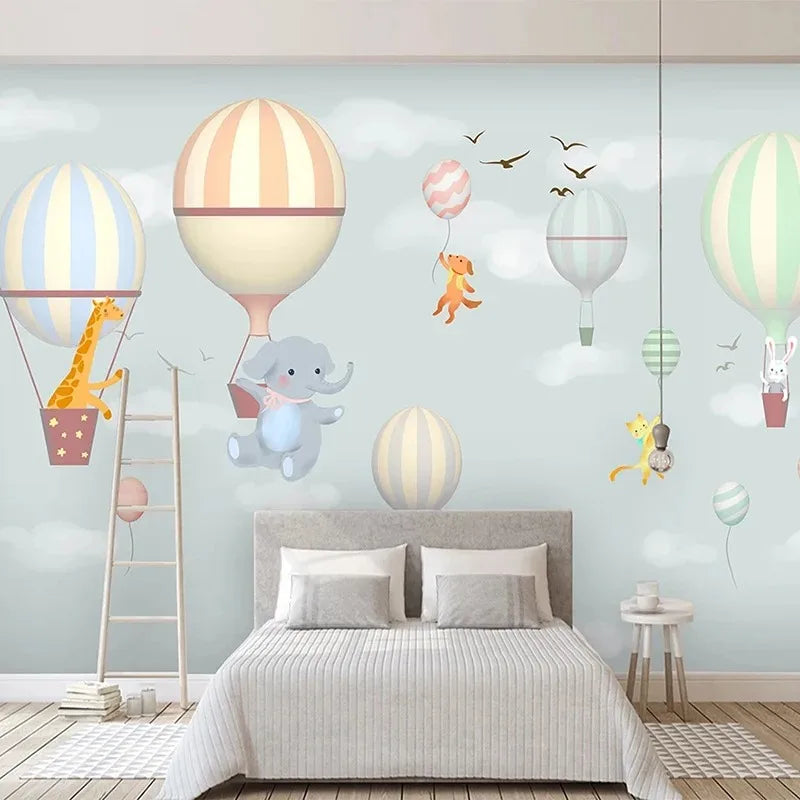 Papier peint panoramique Montgolfières et animaux pastel : montgolfières rayées pastel, éléphant, girafe et petits animaux dans un ciel vert d'eau, posé derrière un lit