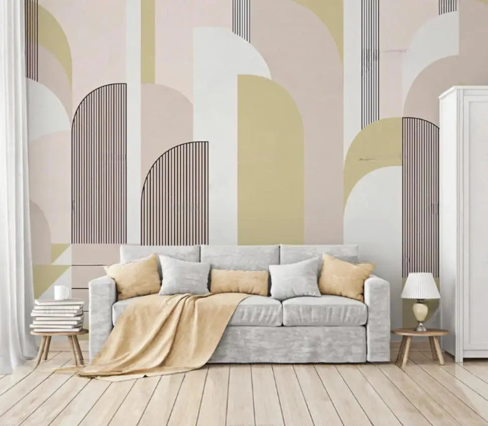 Papier peint panoramique Arches Art déco sable et sauge : arches Art déco en aplats sable, sauge pâle, rose poudré et rayures fines, posé derrière un canapé