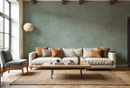 Papier peint effet béton ciré vert sauge : effet béton ciré vert sauge nuancé, derrière un canapé en lin dans un séjour lumineux