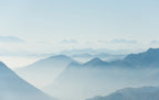 Papier peint panoramique Vallées bleu pâle dans la brume : vue à plat, lignes de crêtes bleu pâle superposées dans la brume, ciel très clair