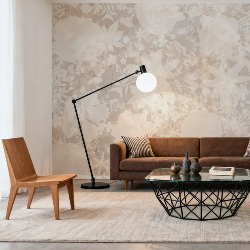 Papier peint effet fleurs estompées lin rosé : effet fleurs estompées lin rosé derrière un canapé en cuir cognac, lampadaire et chaise en bois