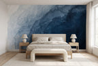 Papier peint panoramique Vague d'encre bleu brume posé derrière un lit en chêne clair, chambre lumineuse