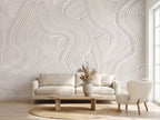 Papier peint effet plâtre peigné blanc cassé posé dans un salon lumineux, canapé en lin et fauteuil bouclette