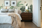 Papier peint panoramique Bananiers et oiseaux sur fond chevron posé derrière la tête de lit d’une chambre