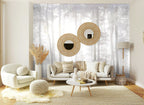 Papier peint panoramique Forêt de pins dans la brume gris perle posé sur le mur d’un salon