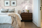 Papier peint panoramique Frondaisons dans la brume rose poudré posé derrière la tête de lit d’une chambre