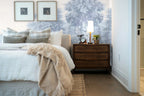 Papier peint panoramique Grands arbres gravés bleu brume posé derrière la tête de lit d’une chambre