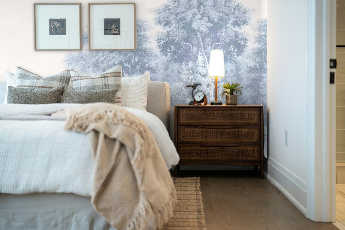 Papier peint panoramique Grands arbres gravés bleu brume posé derrière la tête de lit d’une chambre