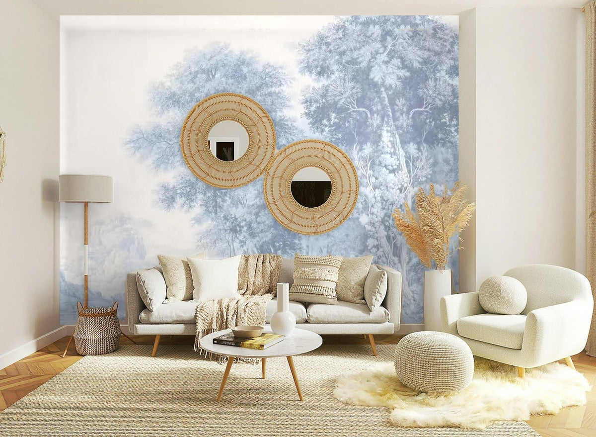 Papier peint panoramique Grands arbres gravés bleu brume posé sur le mur d’un salon clair