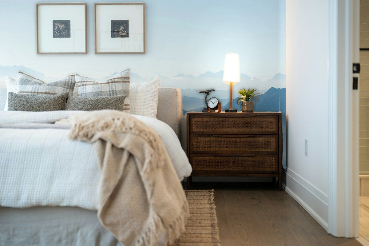 Papier peint panoramique Vallées bleu pâle dans la brume posé derrière la tête de lit d’une chambre